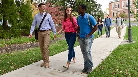 Students walking along a wooded sidewalk.